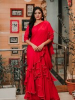 A pre-draped saree in a vibrant red, made from pure chiffon, adding a touch of glamour.