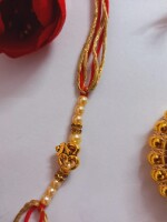 Red and yellow om rakhi for bhai complete with mini nariyal roli, and chawal